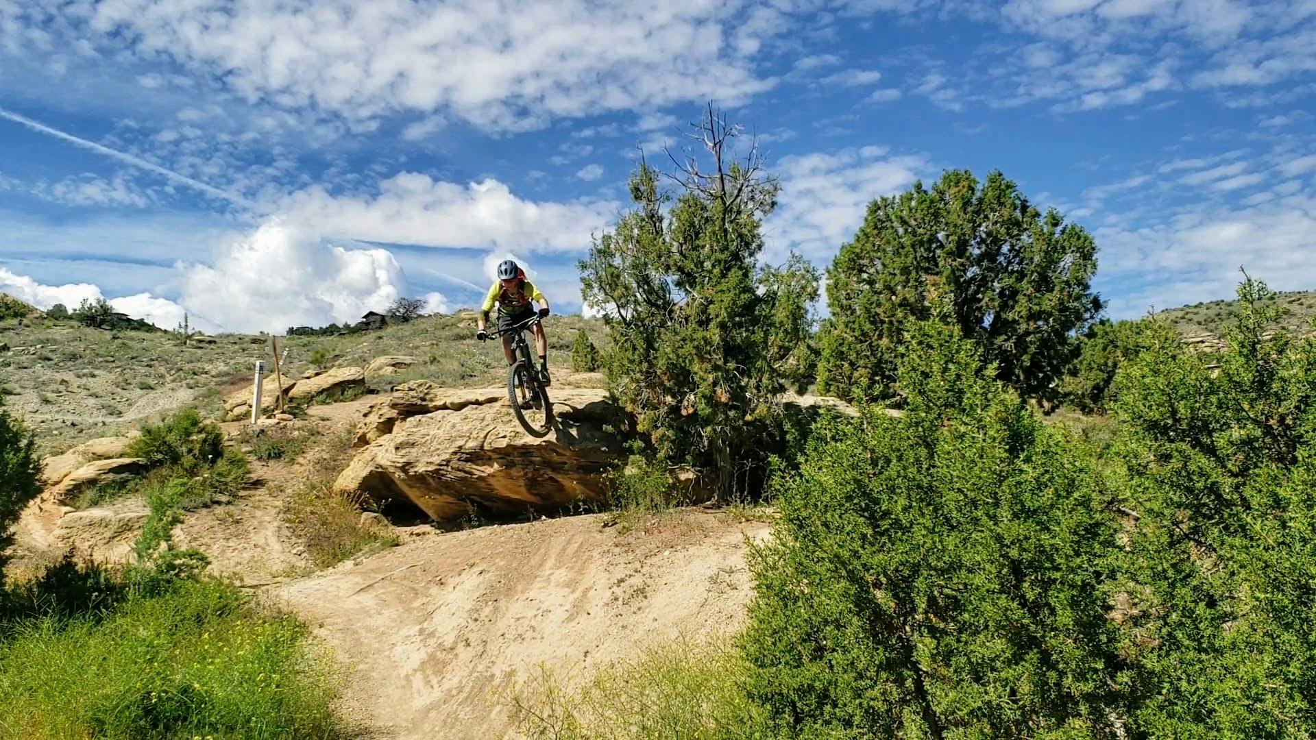 A mountain biker going off a rocky boulder