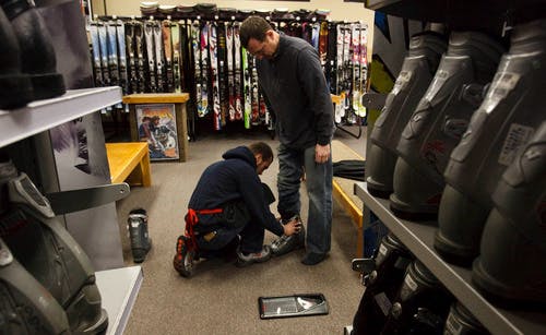 A man trying on rental ski boots in a ski shop. 