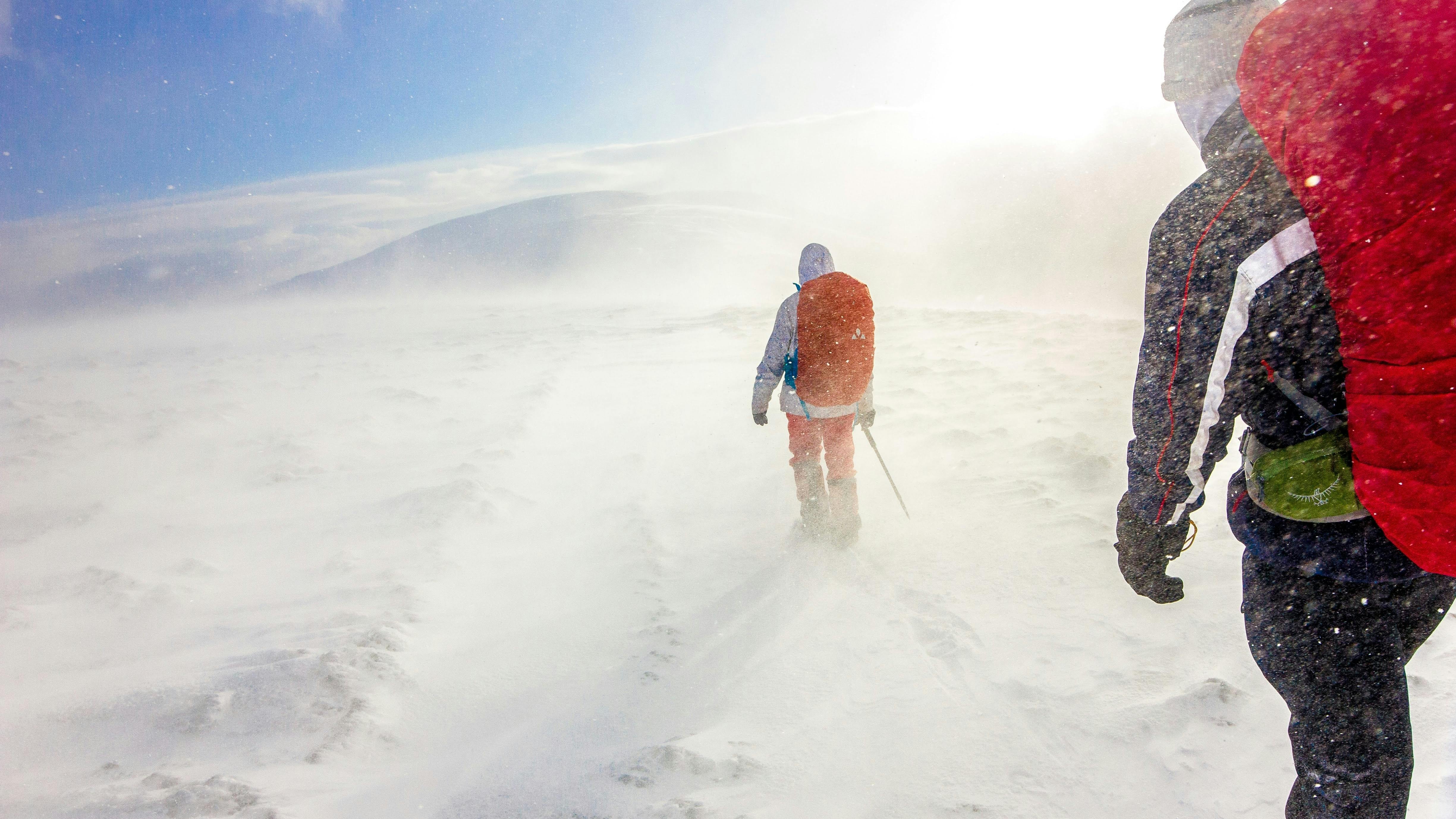 Two people hike across a snowy plain