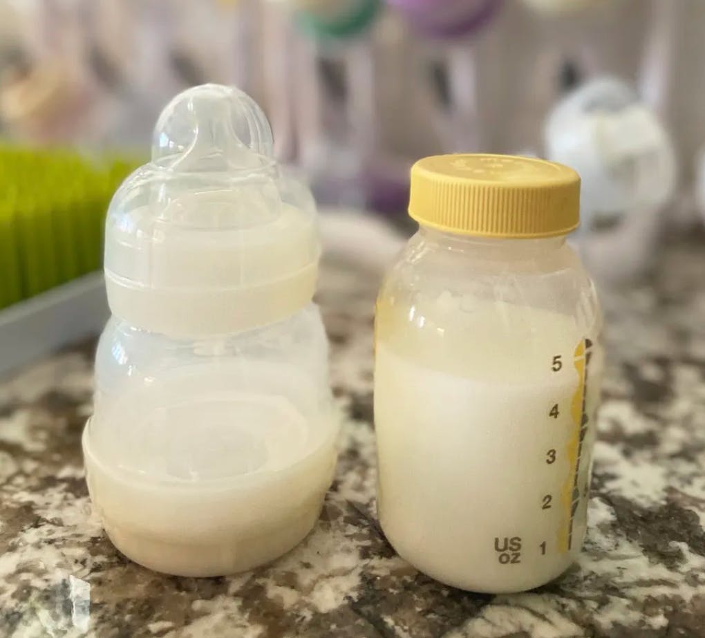 Two baby bottles with different milks sit next to each other on a counter. 