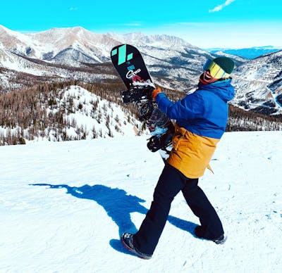 A snowboarder wearing the Volcom Women's Elm Stretch GORE-TEX® Bib Pants.
