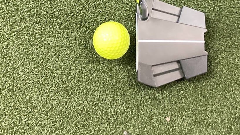 The Odyssey Eleven Tour Lined Putter in front of a golf ball. 