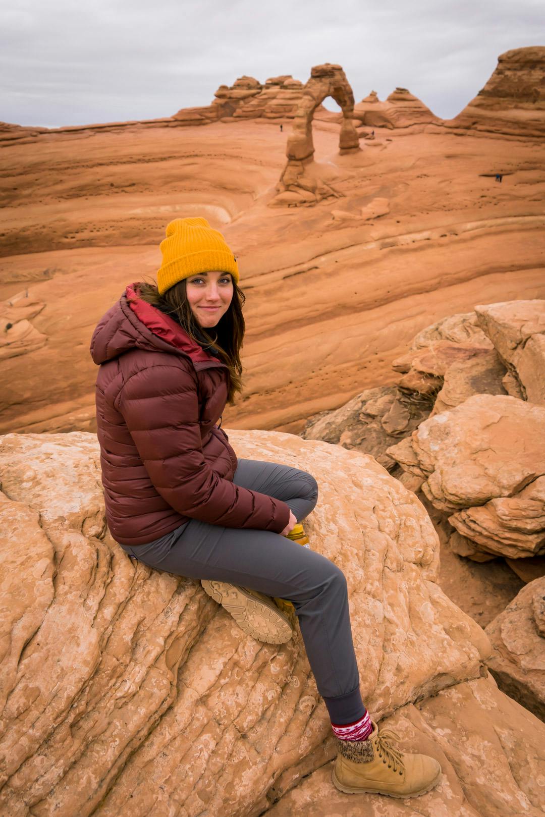 A girl sitting on a rock wearing the Patagonia Hi Loft Jacket. 