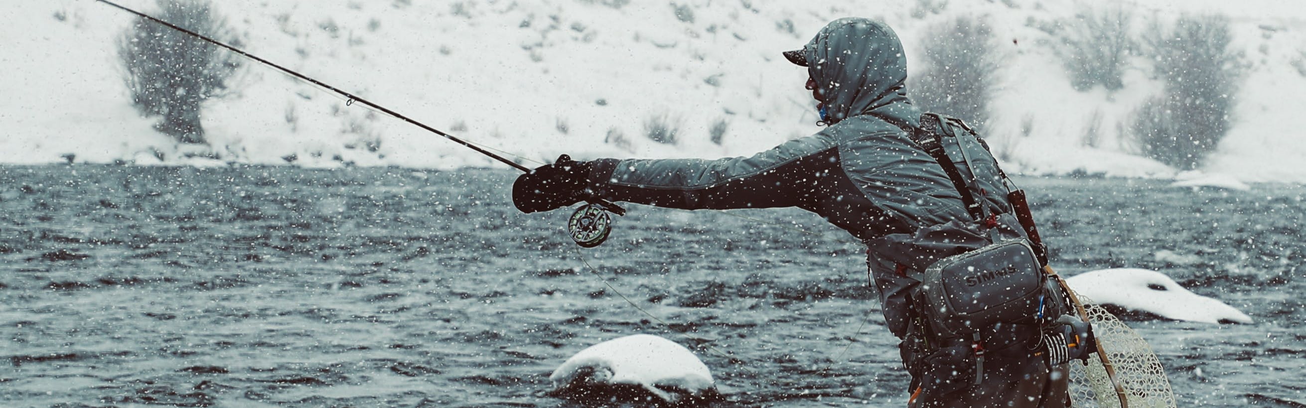 Man in jacket fly fishing in winter