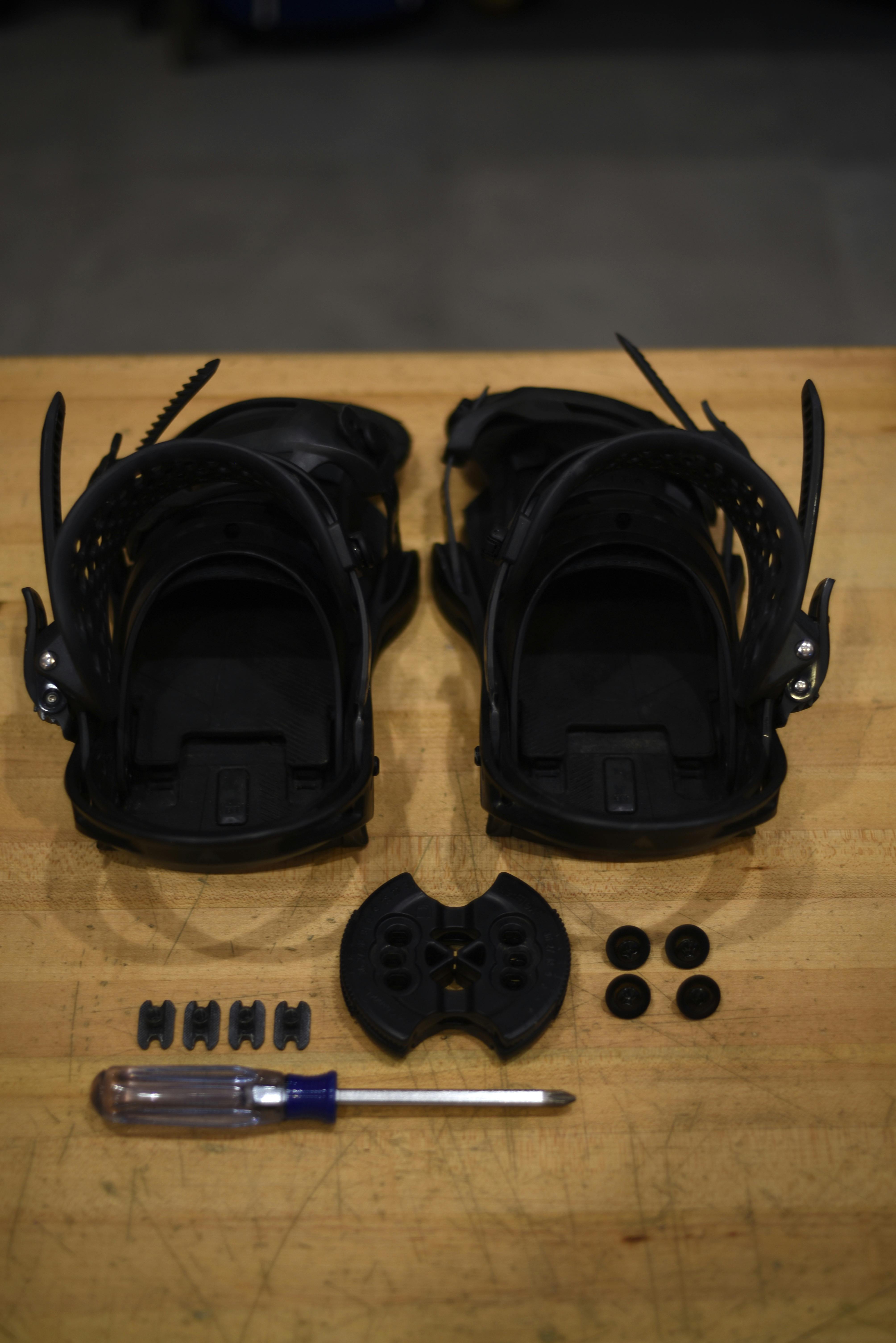 A pair of black snowboard bindings and the equipment needed to mount them