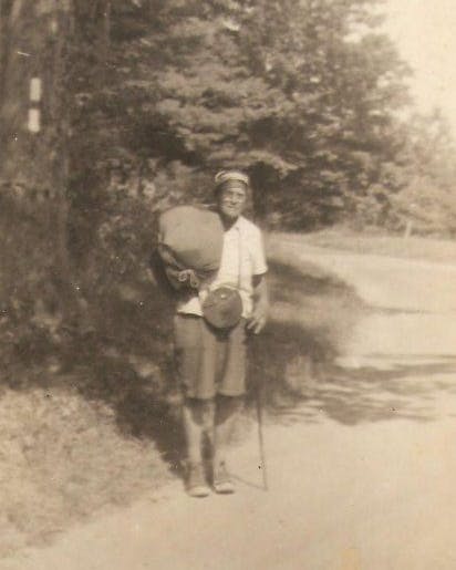 Black and white photo of Emma Gatewood on a trail with a hiking stick and satchel