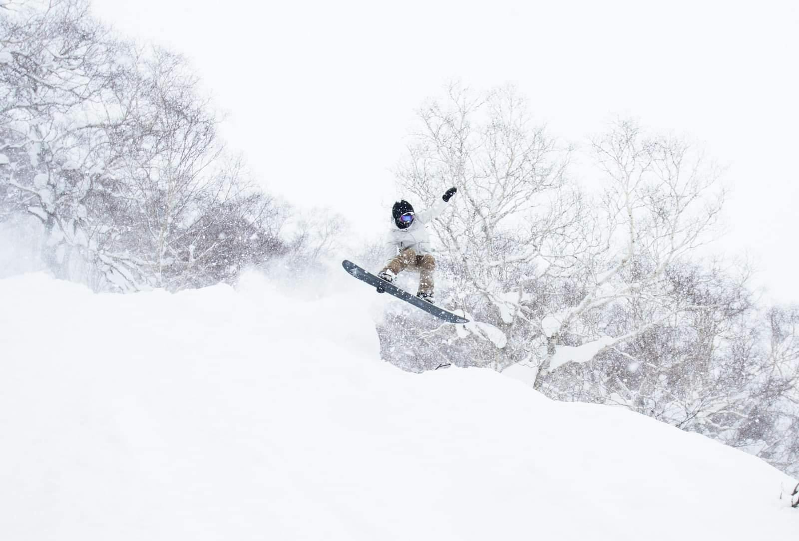 A snowboarder executes a jump on a snowy day