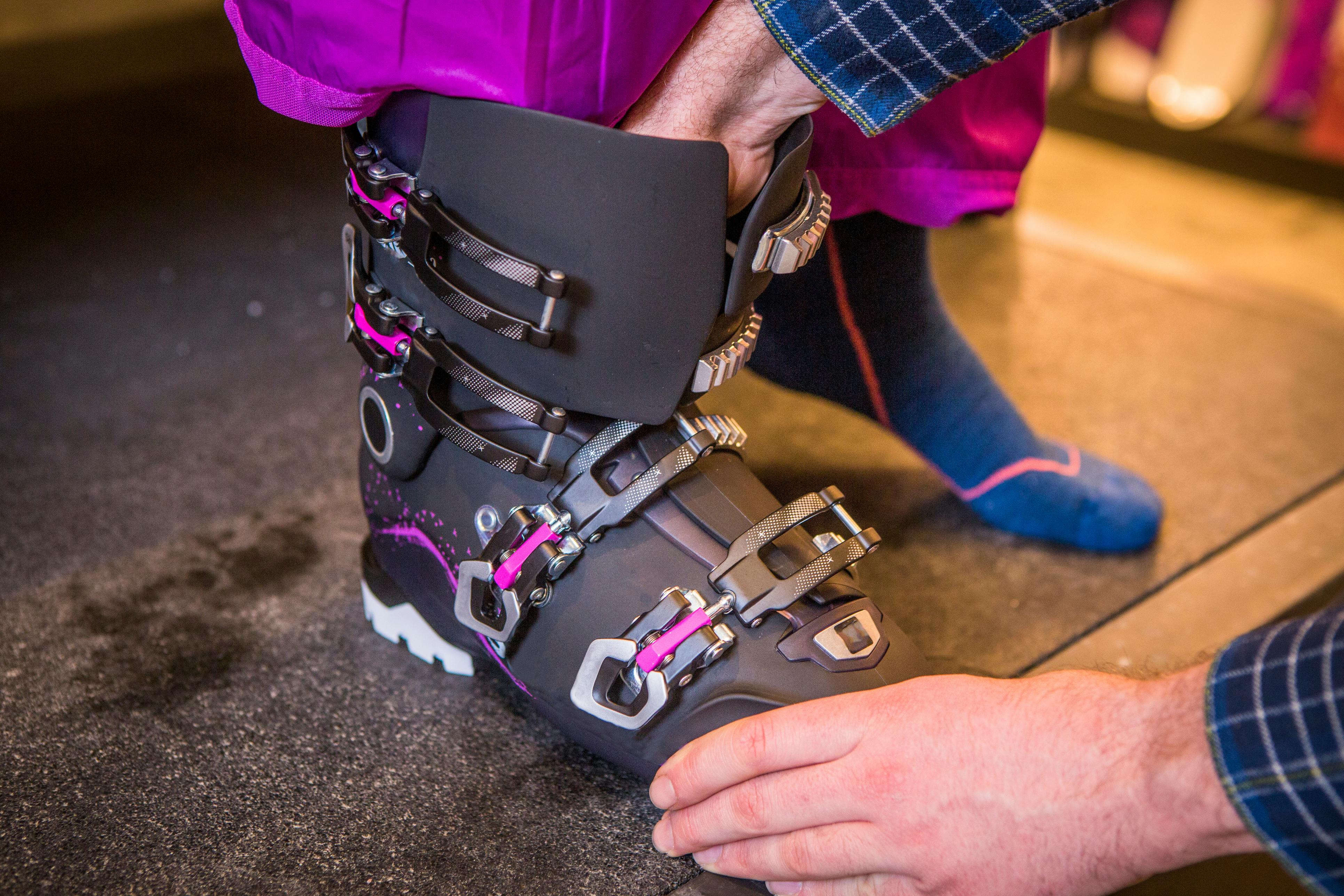 A person helps a child try on a ski boot