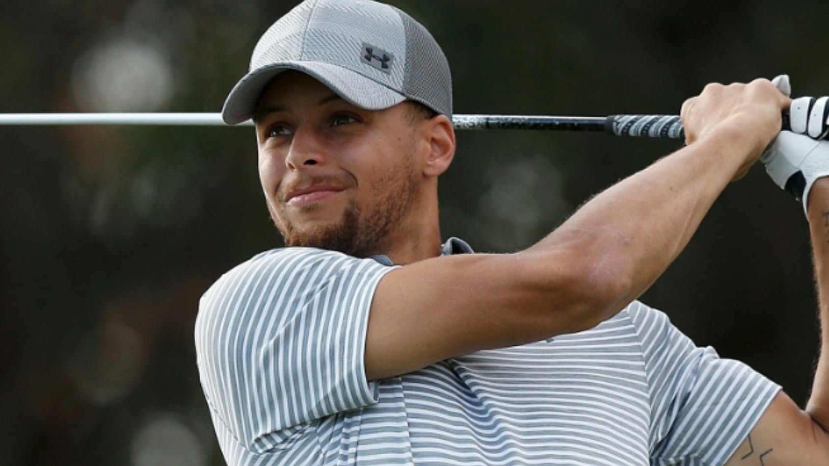 Golfer in a striped shirt swinging a golf club