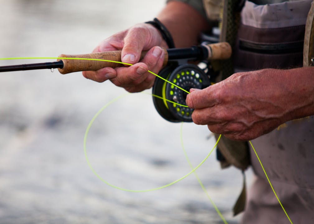 Closeup on a fly reel and fly line held by a fisherman