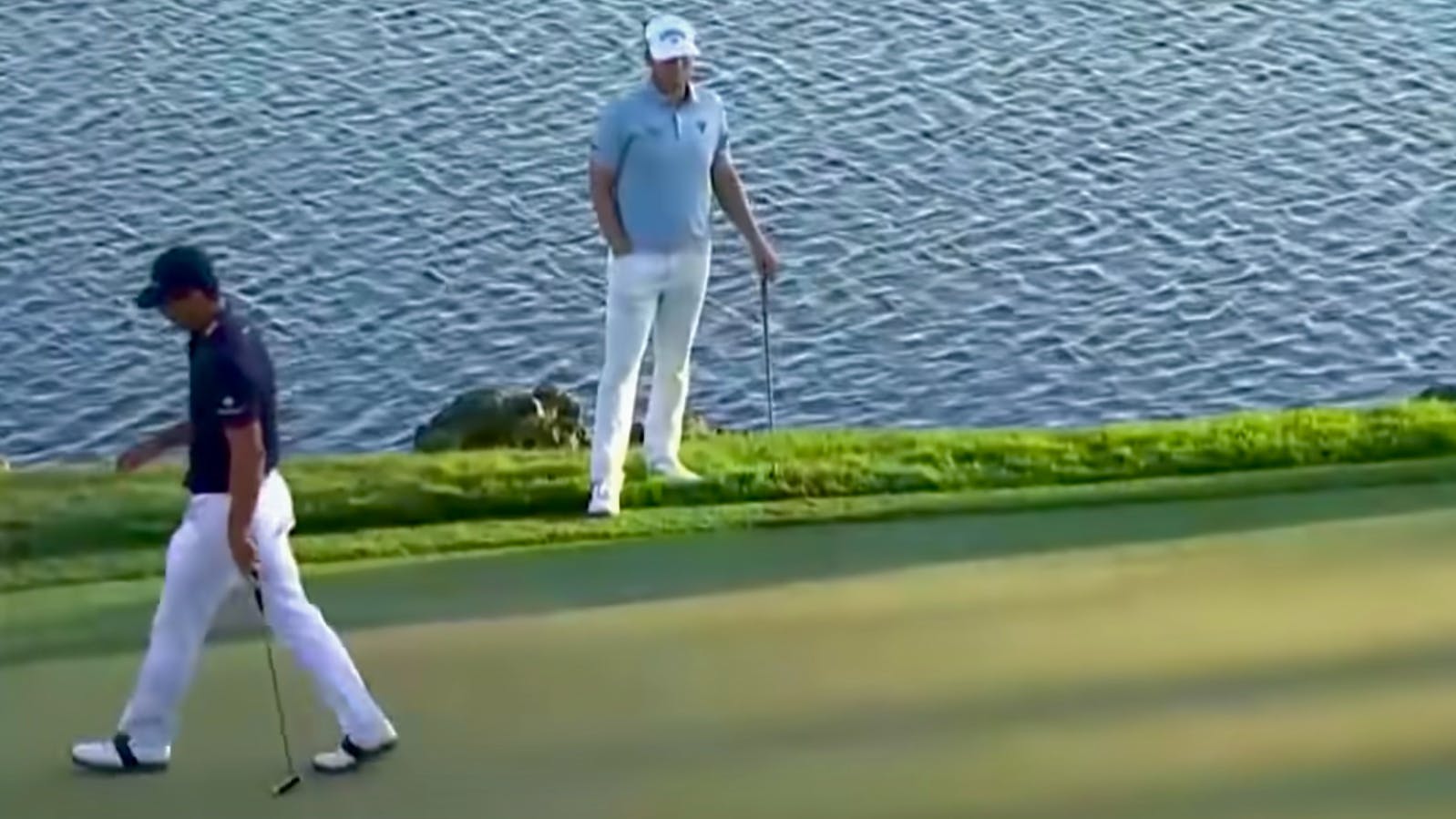 A screenshot from the Arnold Palmer Invitational tournament with two golfers walking next to a water feature. 