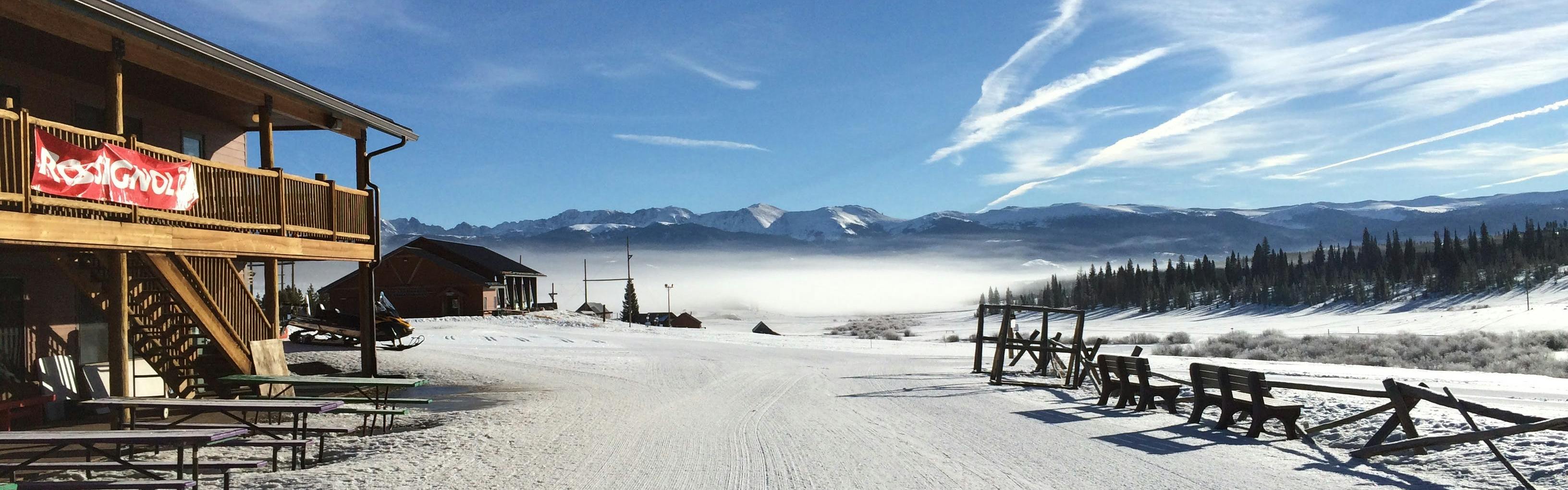 A snowy ski track with foggy mountains in the background. 