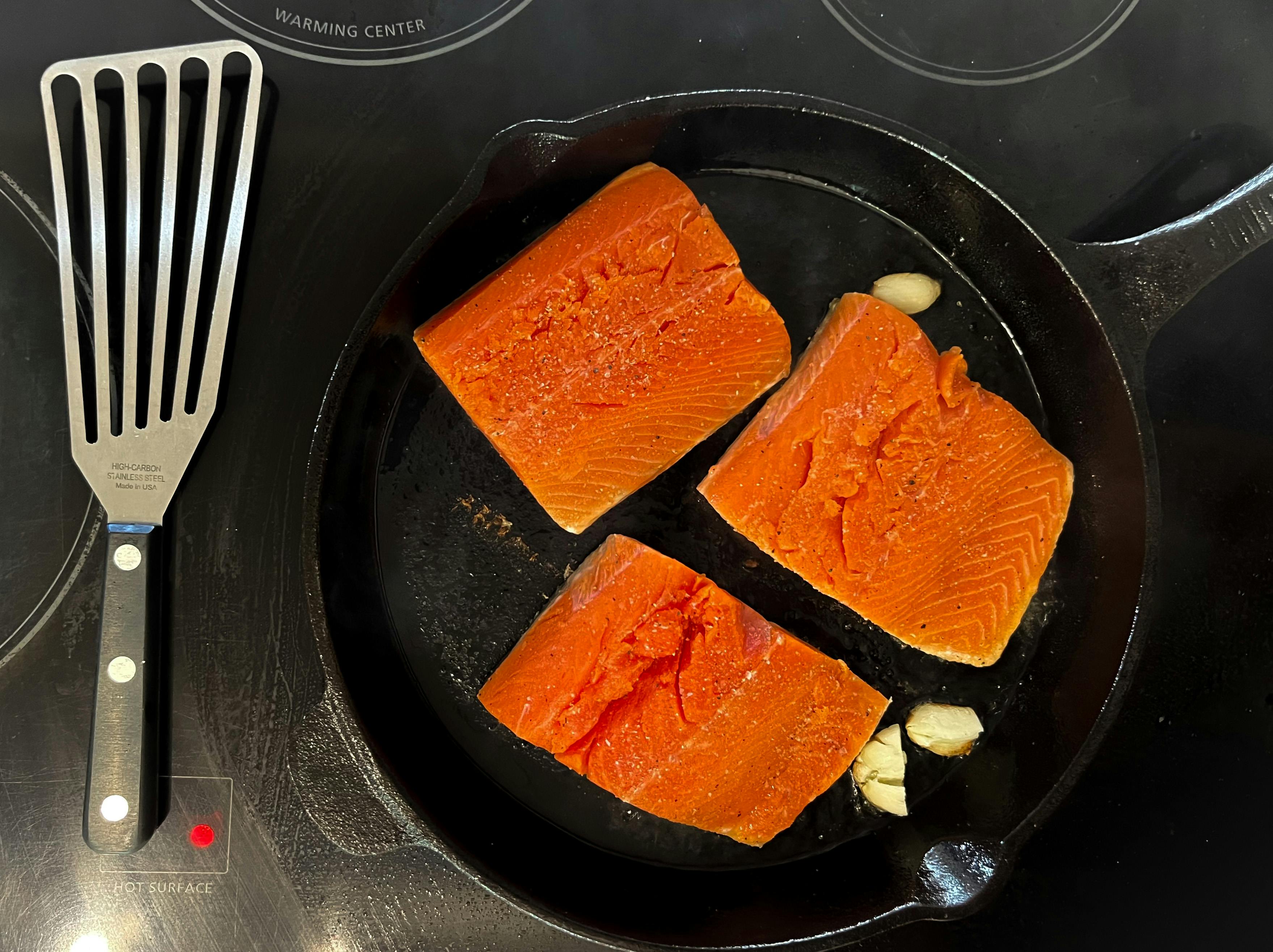 Salmon fillets on pan with crushed garlic