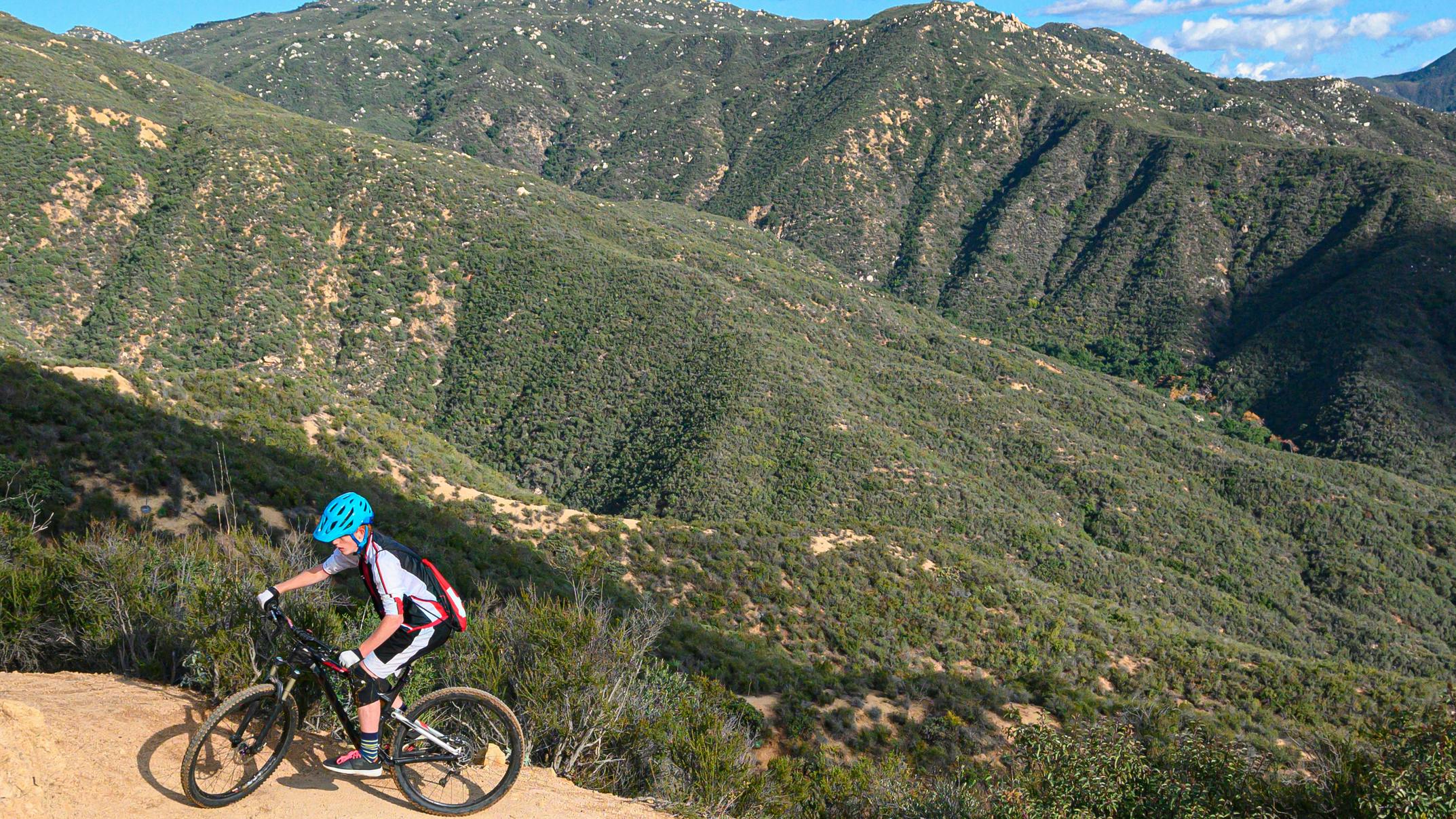 A mountain biker navigates a dusty, rocky trail in California.