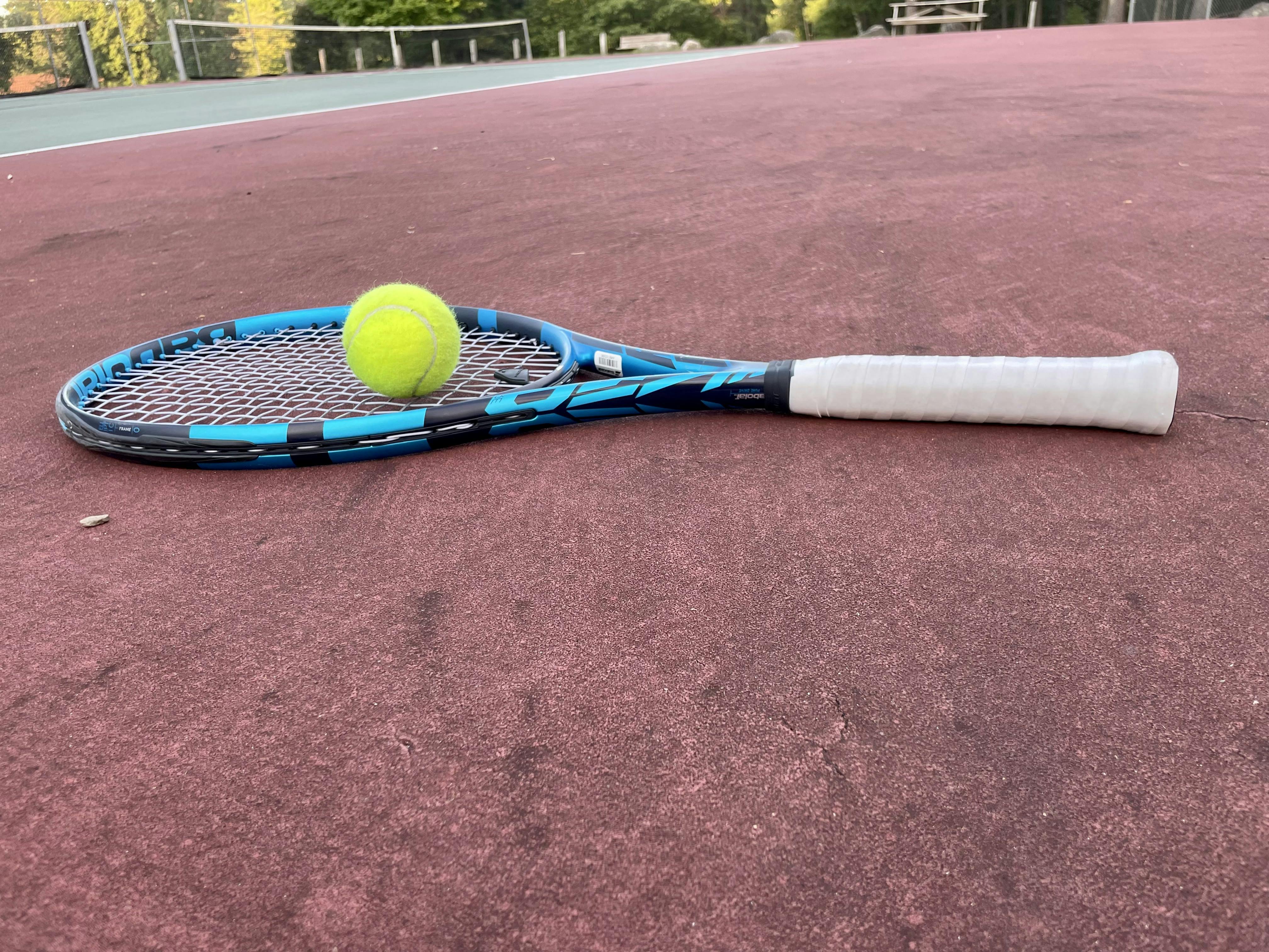 A Babolat Pure Drive 100 2021 lying on a tennis court.