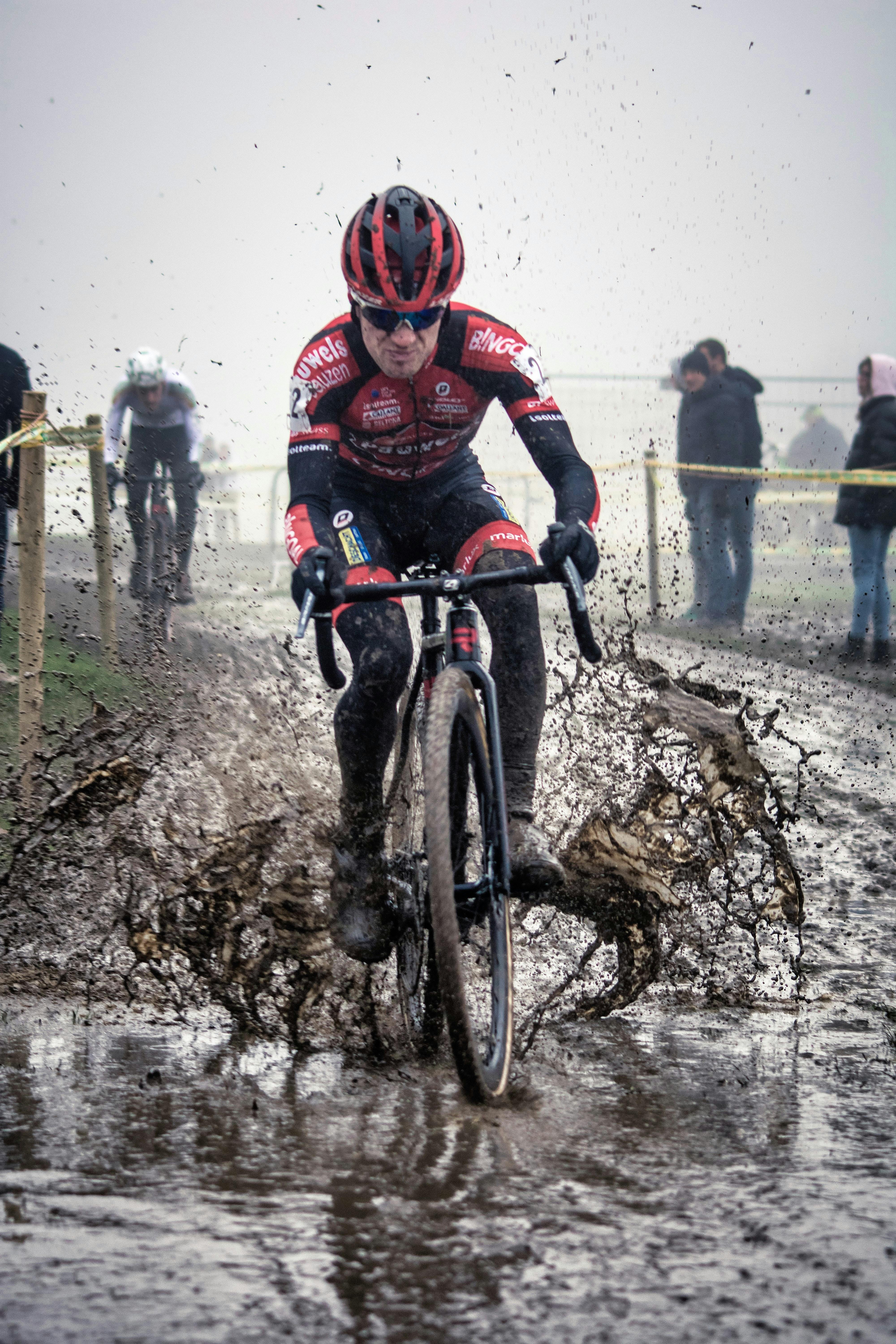 A cyclocross rider sloshing his bike through wet mud.