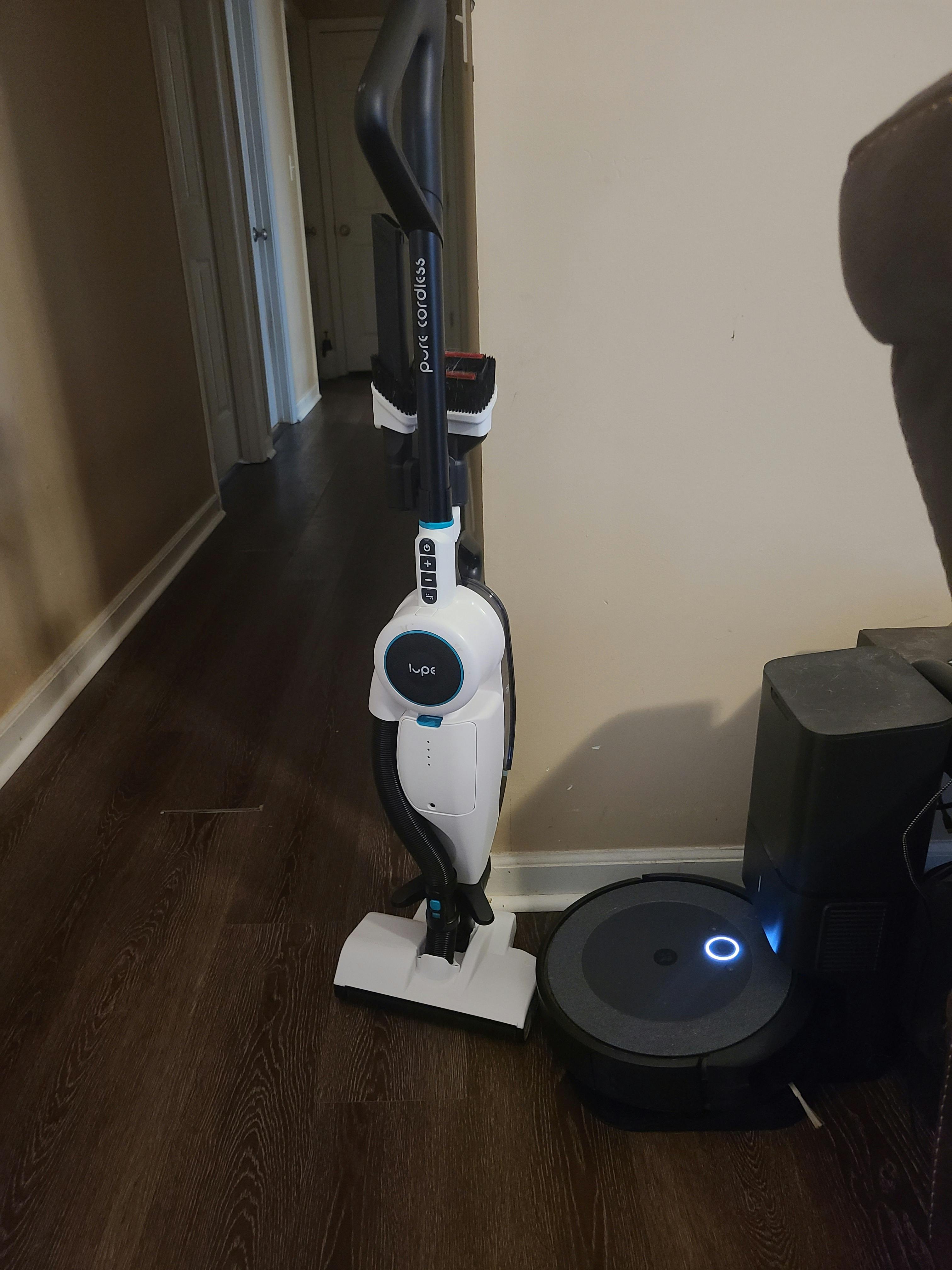 A Lupe Cordless Vacuum next to a Robot Vacuum. 