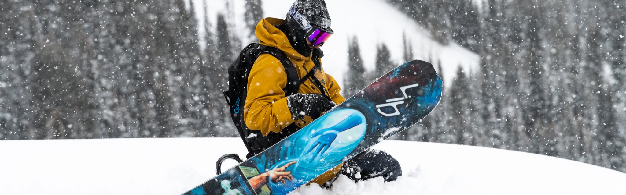 Someone kneels in the snow with their snowboard.