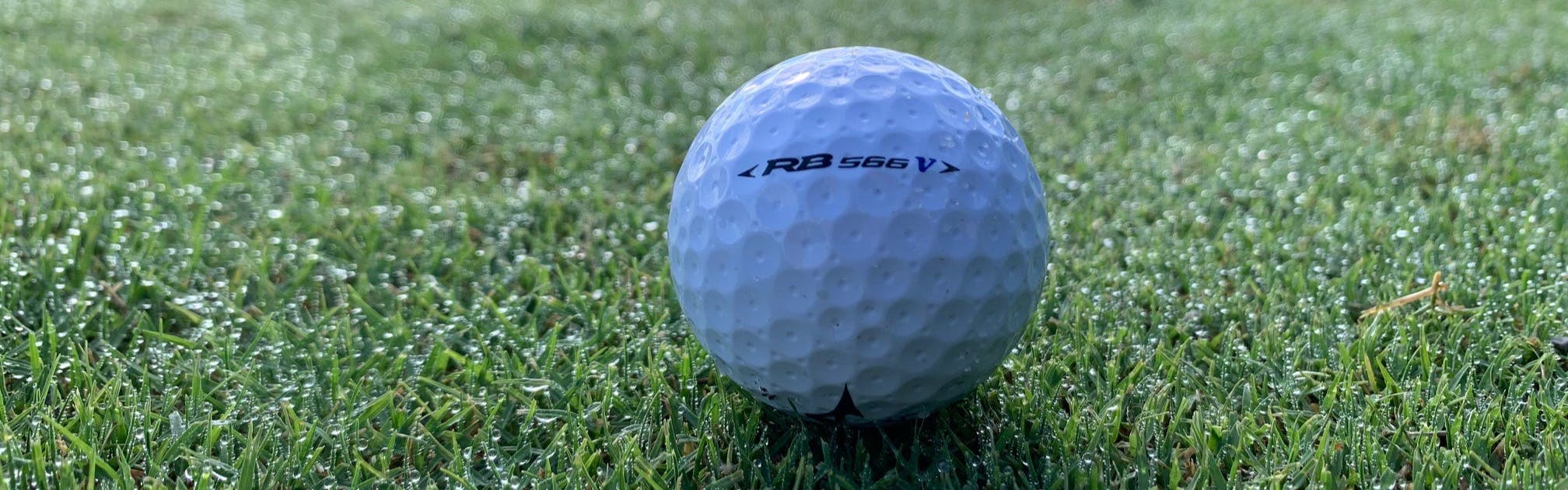 A Mizuno RB 566V Golf Ball lying on the grass.