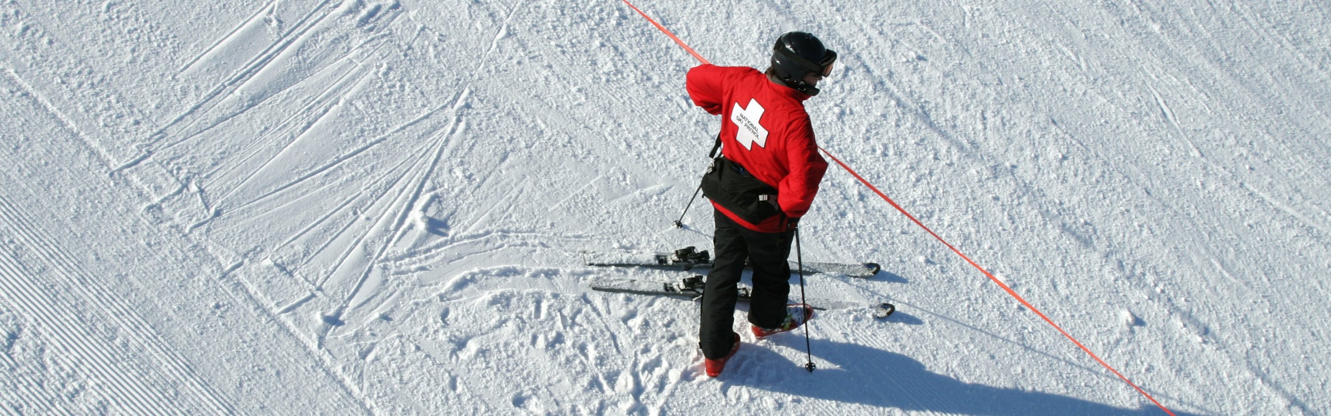 A member of the ski patrol checks a red boundary rope
