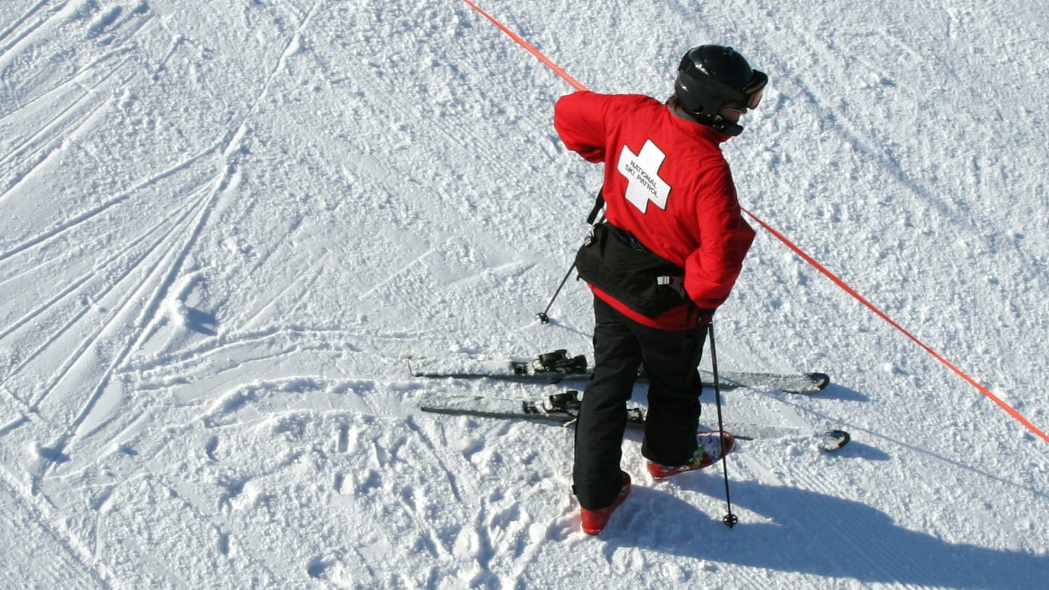 A member of the ski patrol checks a red boundary rope.