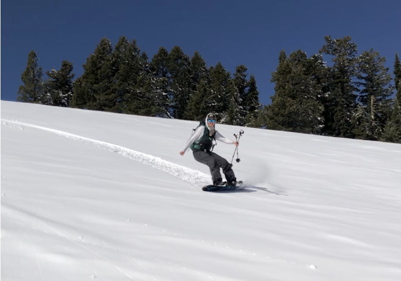 A splitboarder turning down a snowy trail. 