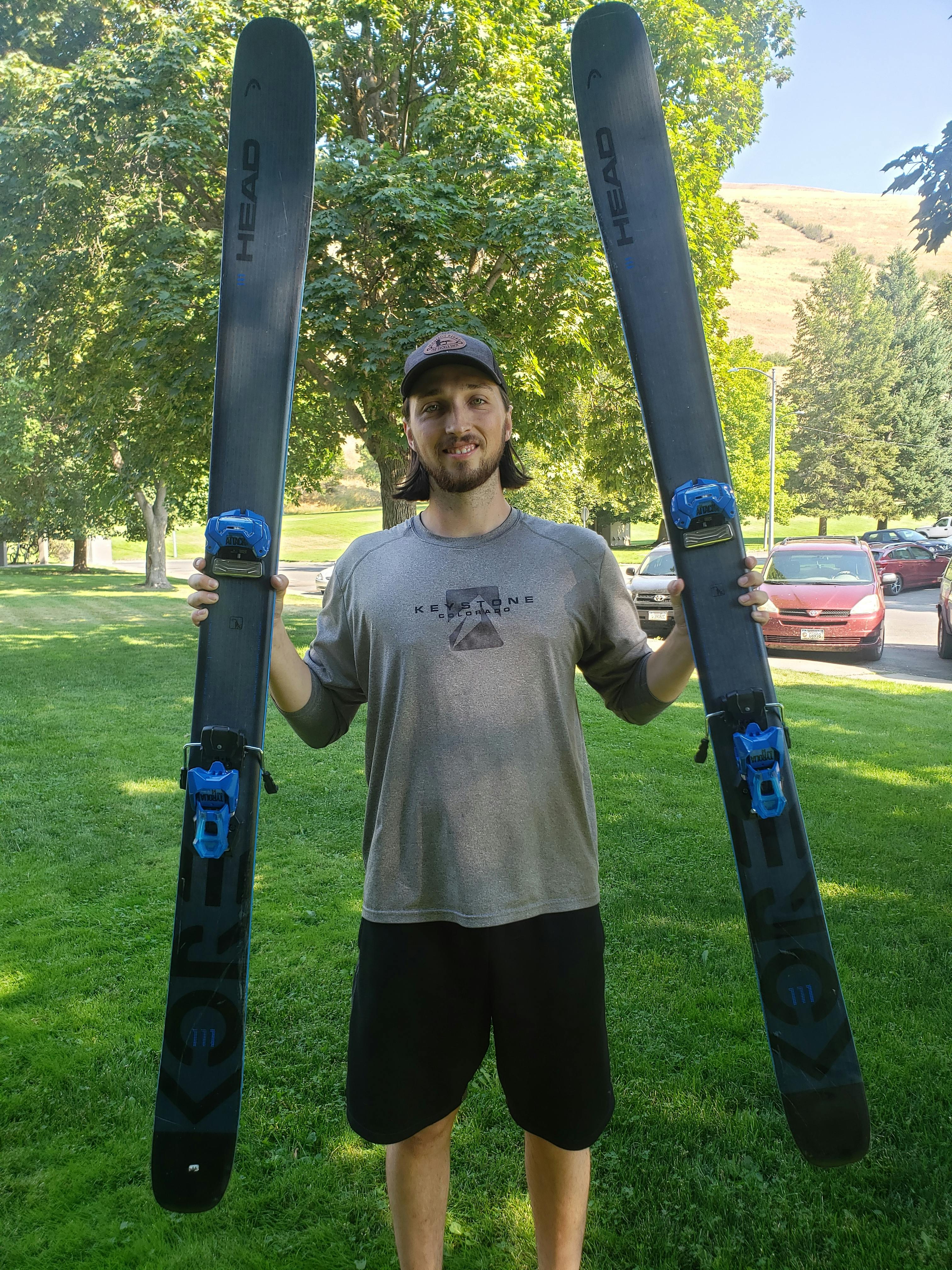 A man holding skis mounted with the Tyrolia Attack 14 Gw Ski Bindings.