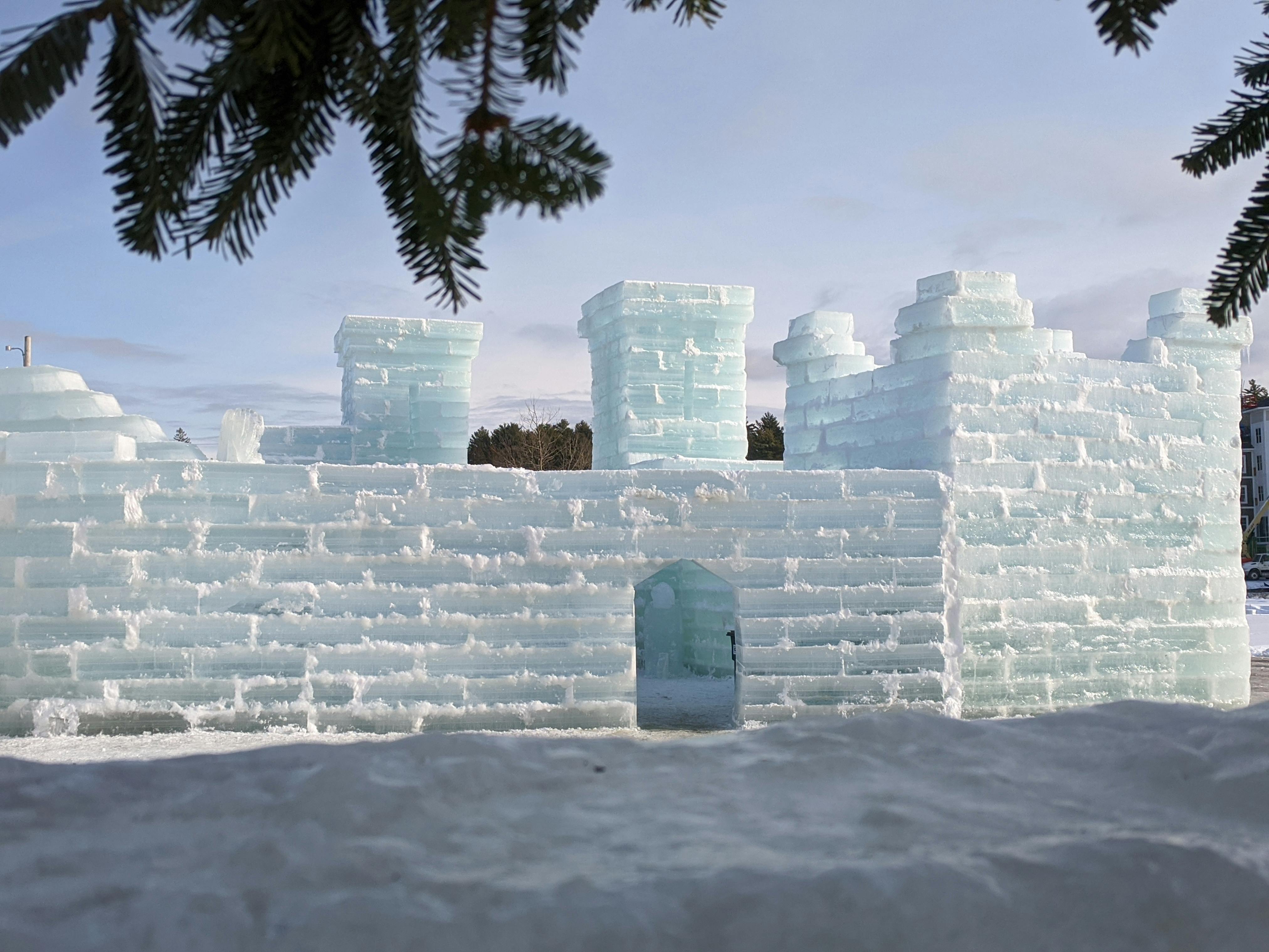 An ice castle rises from the snow on a blue-sky day.