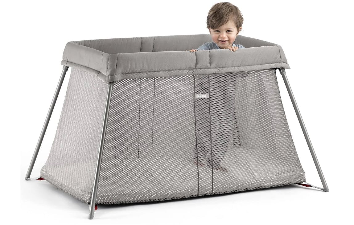 A child peaks out of the BabyBjörn Travel Crib Light.