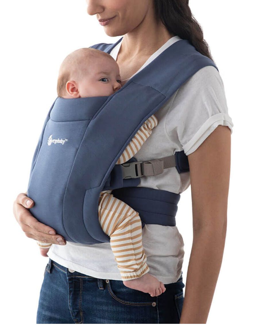Woman using the Embrace Cozy Newborn Carrier.