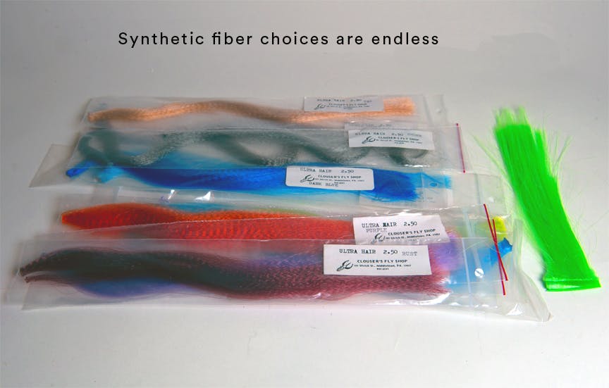 A collection of the author's fur choices - a whole rainbow of color. They are each in their own plastic baggie. The text reads, "Synthetic fiber choices are endless."