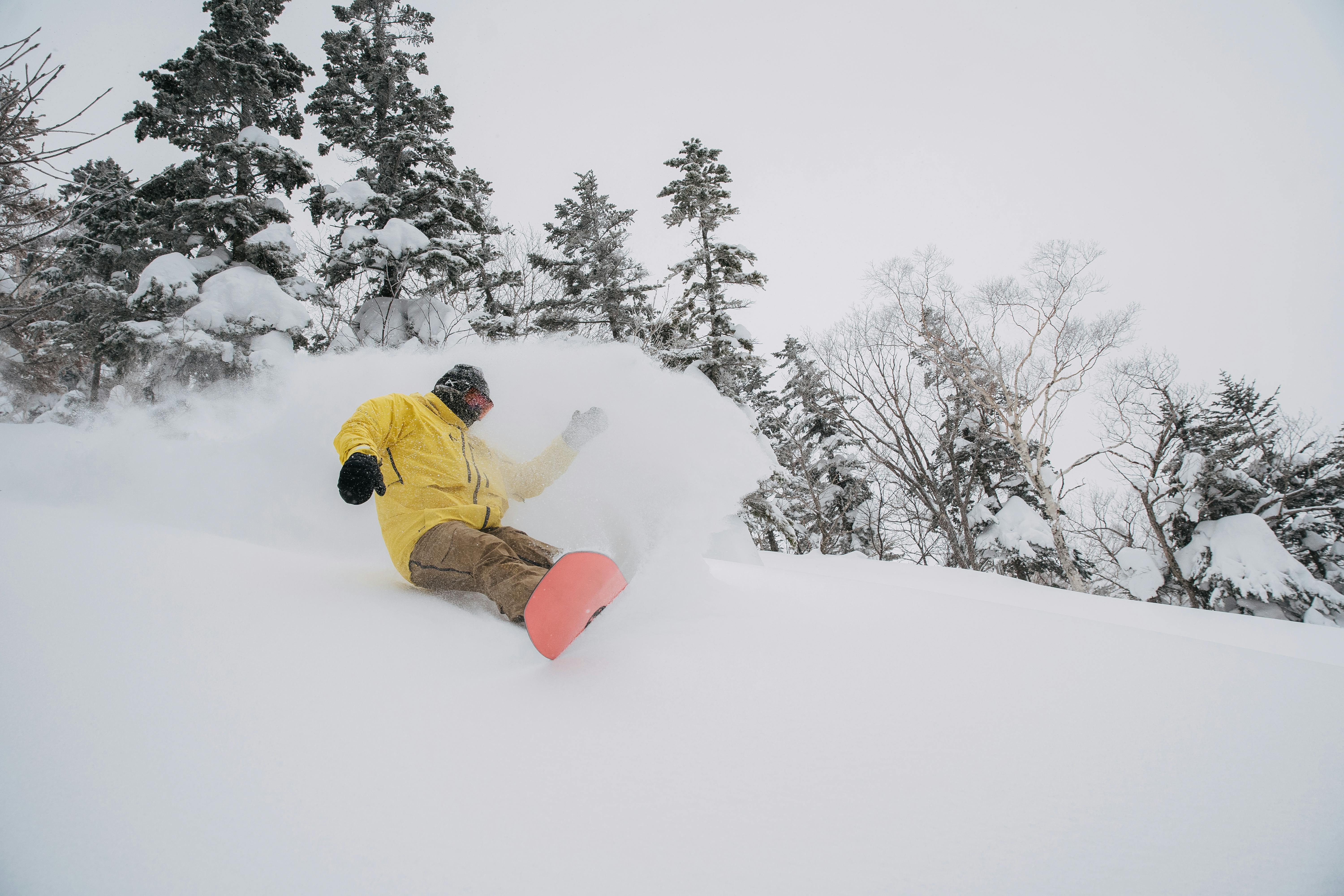 Downing carves on his Burton board, sending a spray of powder off behind him on a gray day.
