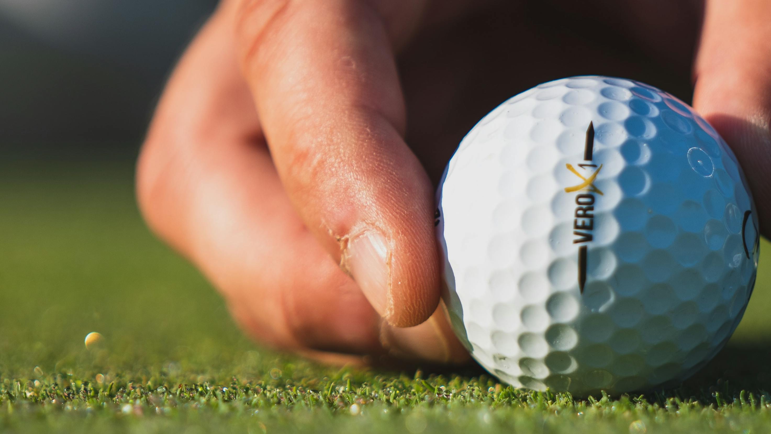 A man places a golf ball down.