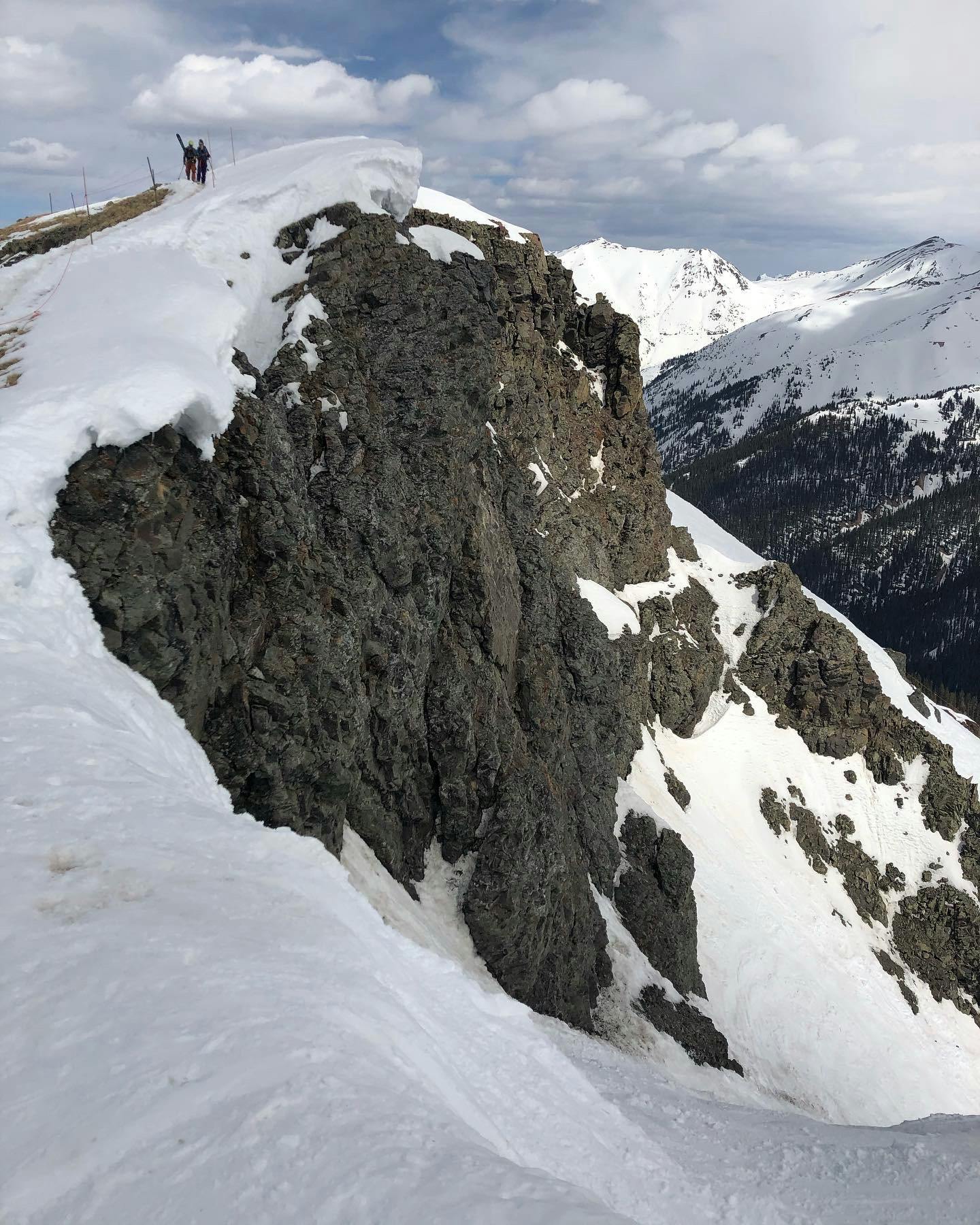 Skiers walking up a steel cliff at Silverton Mountain. 