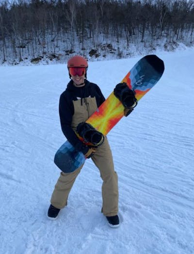 A snowboarder holding the Lib Tech T.Rice Golden Orca Snowboard.