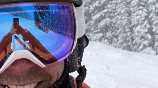A man at a ski resort wearing the Smith Skyline XL Goggles.