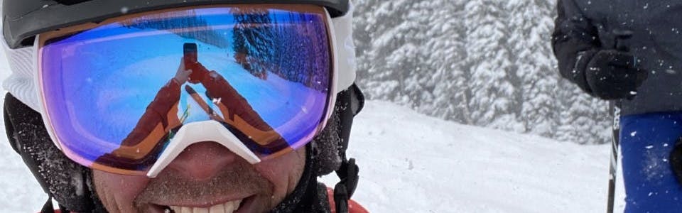 A man at a ski resort wearing the Smith Skyline XL Goggles.