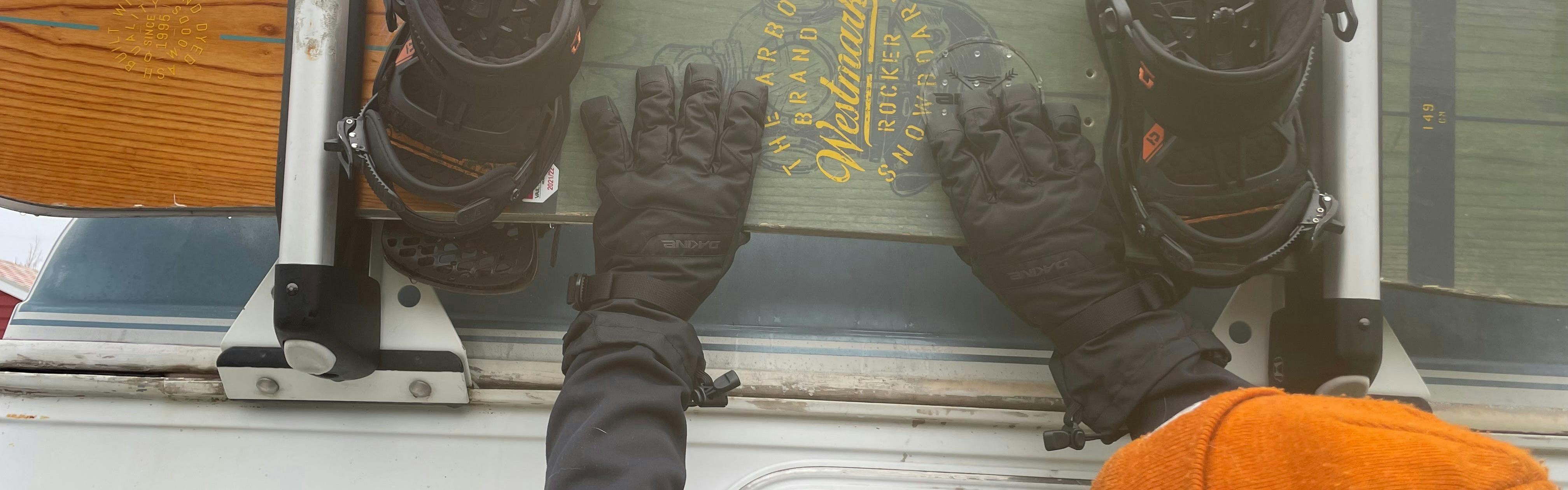 The Dakine Men's Blazer Gloves grabbing a snowboard. 