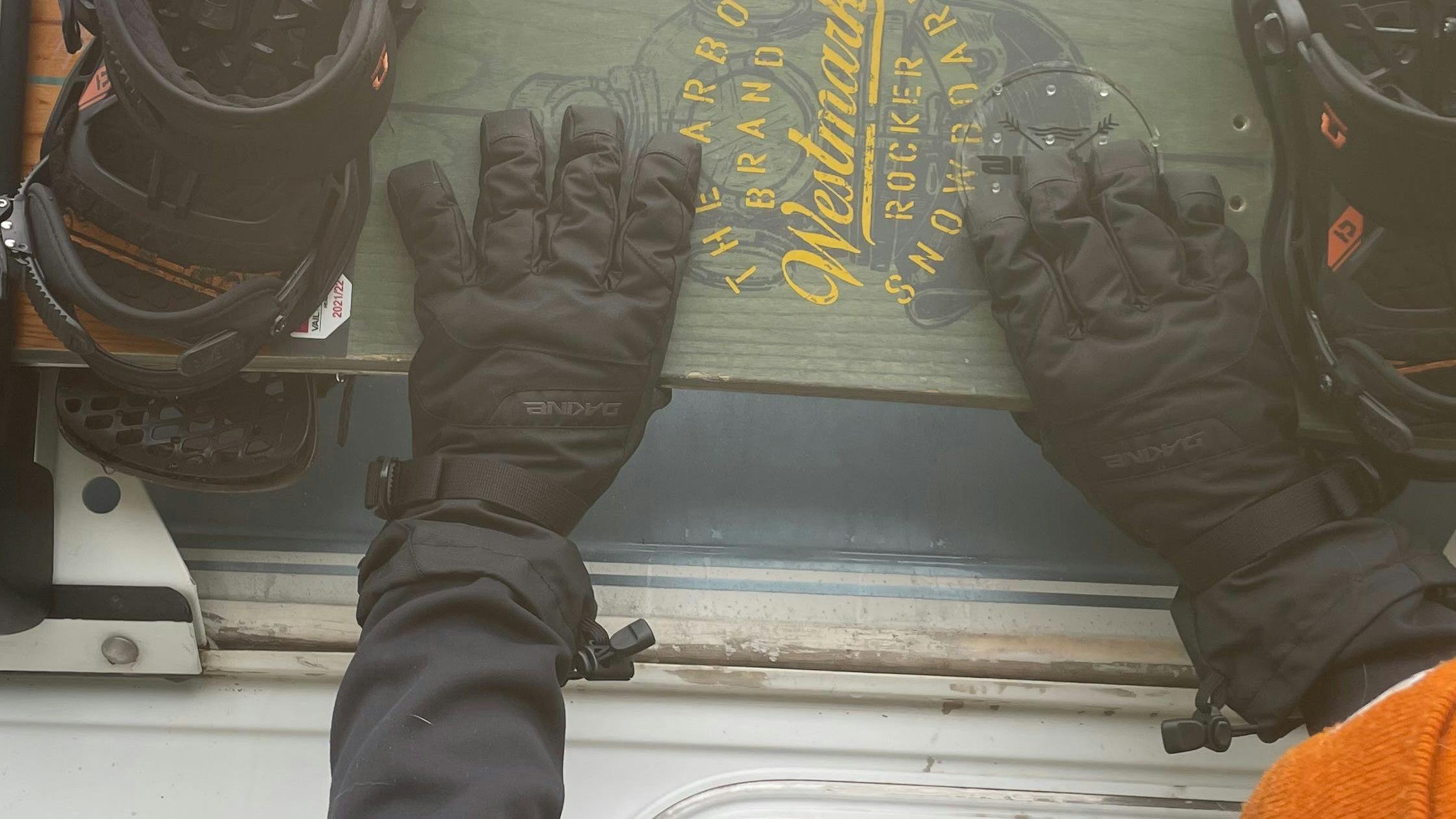 The Dakine Men's Blazer Gloves grabbing a snowboard. 