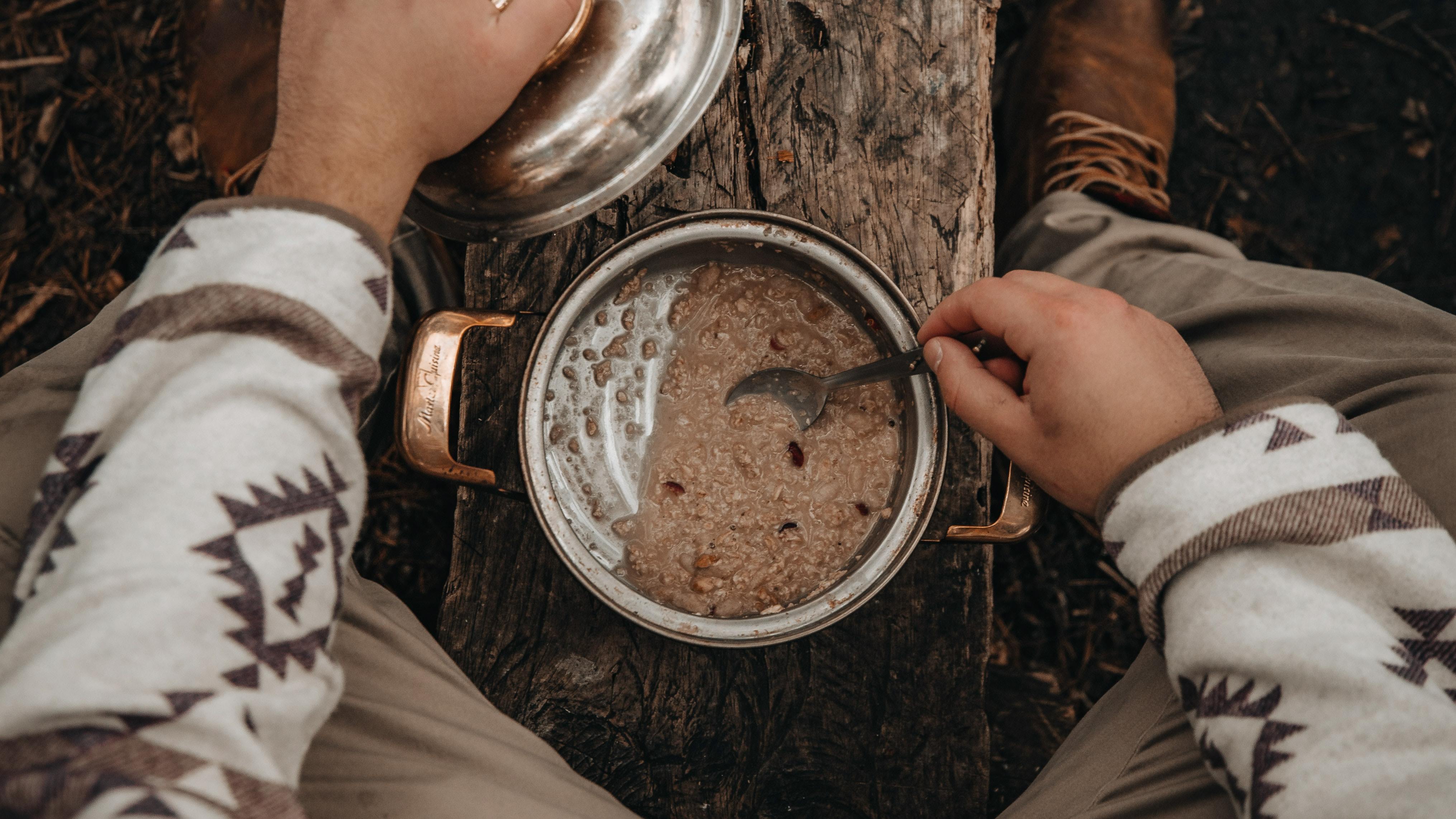 Aerial view of a person preparing oatmeal in a pot outdoors