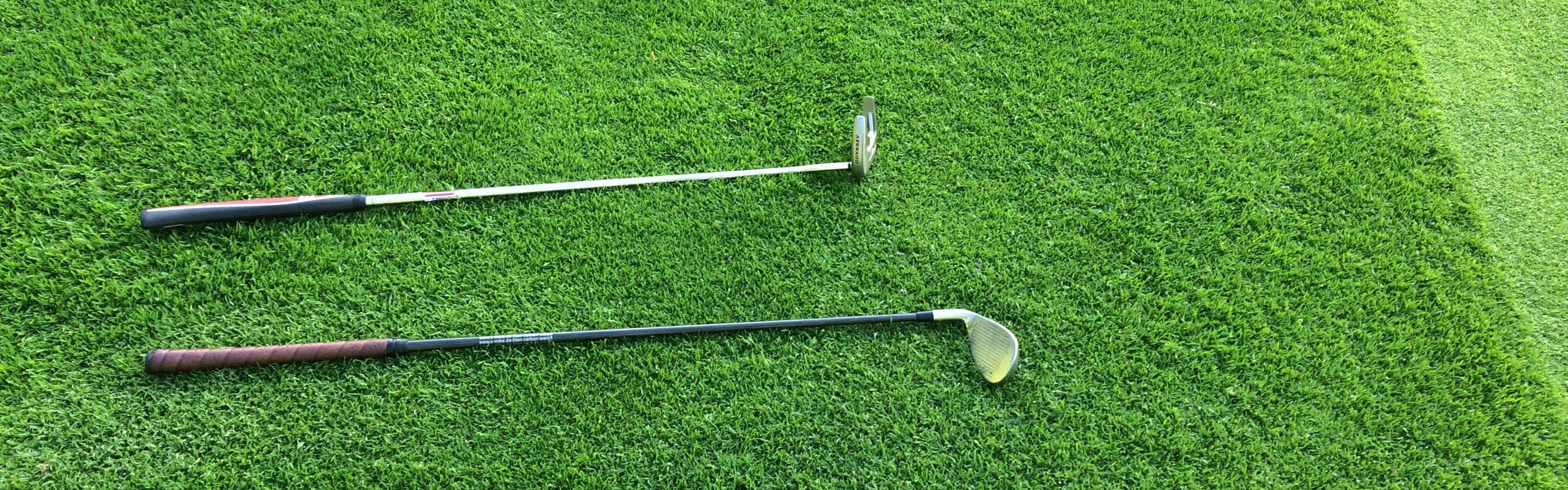 Two golf clubs lay next to each other.
