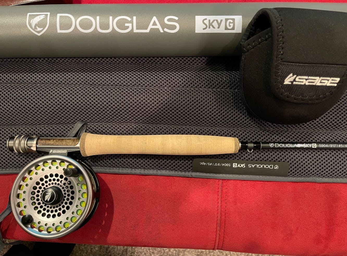 The Douglas SKY G Fly Rod laying on a table with its case and a Sage reel.