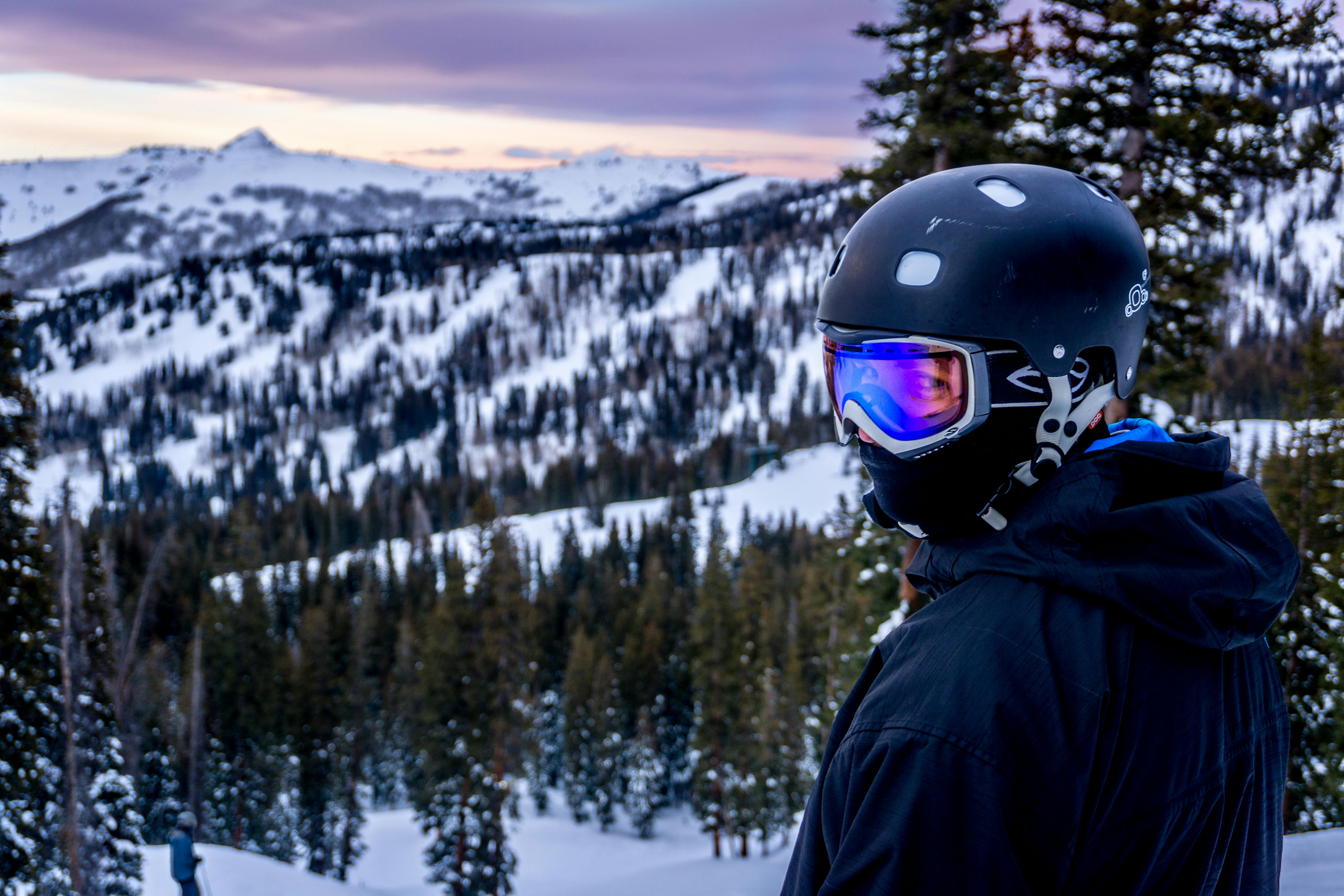 A skier wearing a helmet and goggles looking down at a snowy mountain. 