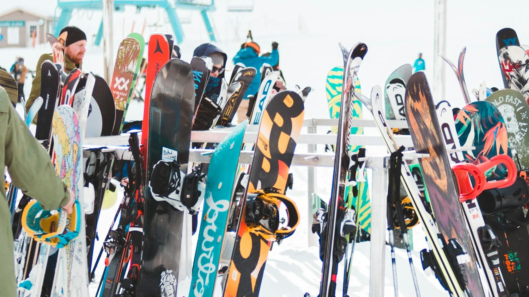 A rack of colorful snowboards and skis at a resort