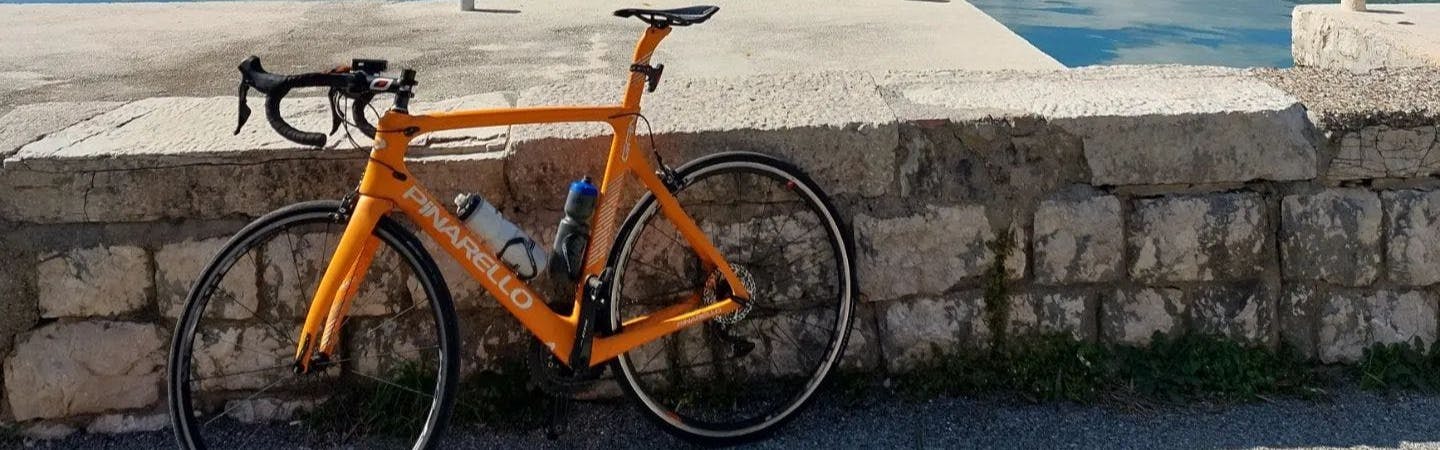 A road bike sitting against a wall. The bike has LOOK Plus pedals on it.
