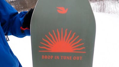 Bird and sun graphic on the bottom of the Arbor Westmark Camber snowboard