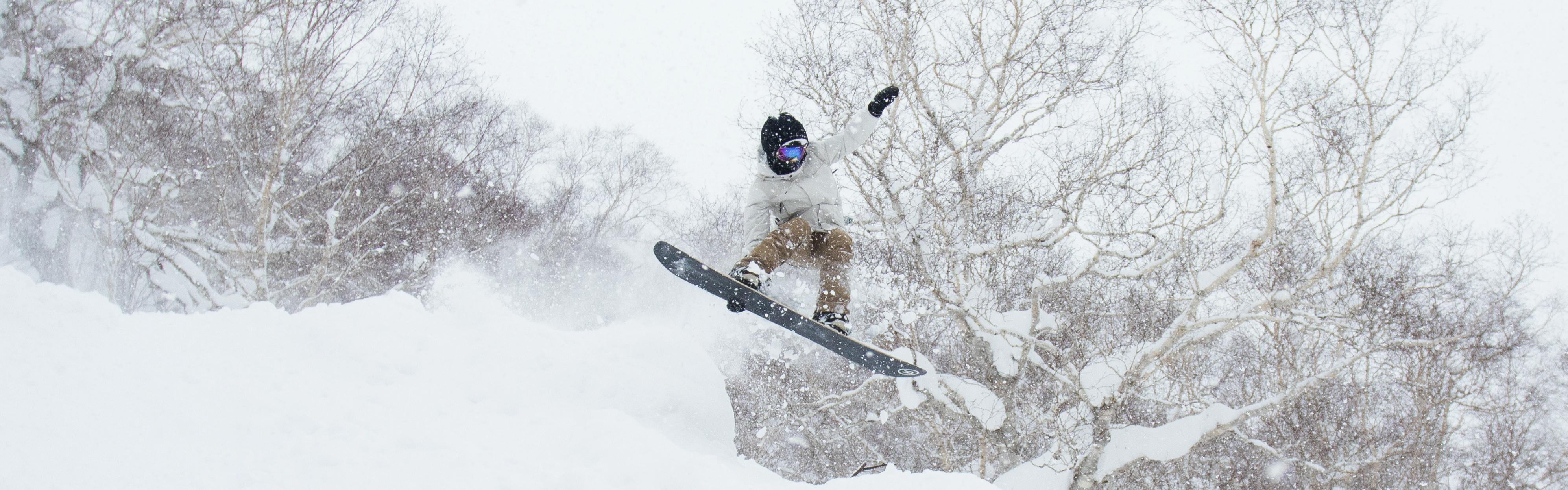 Someone jumps on a snowboard through the powder.