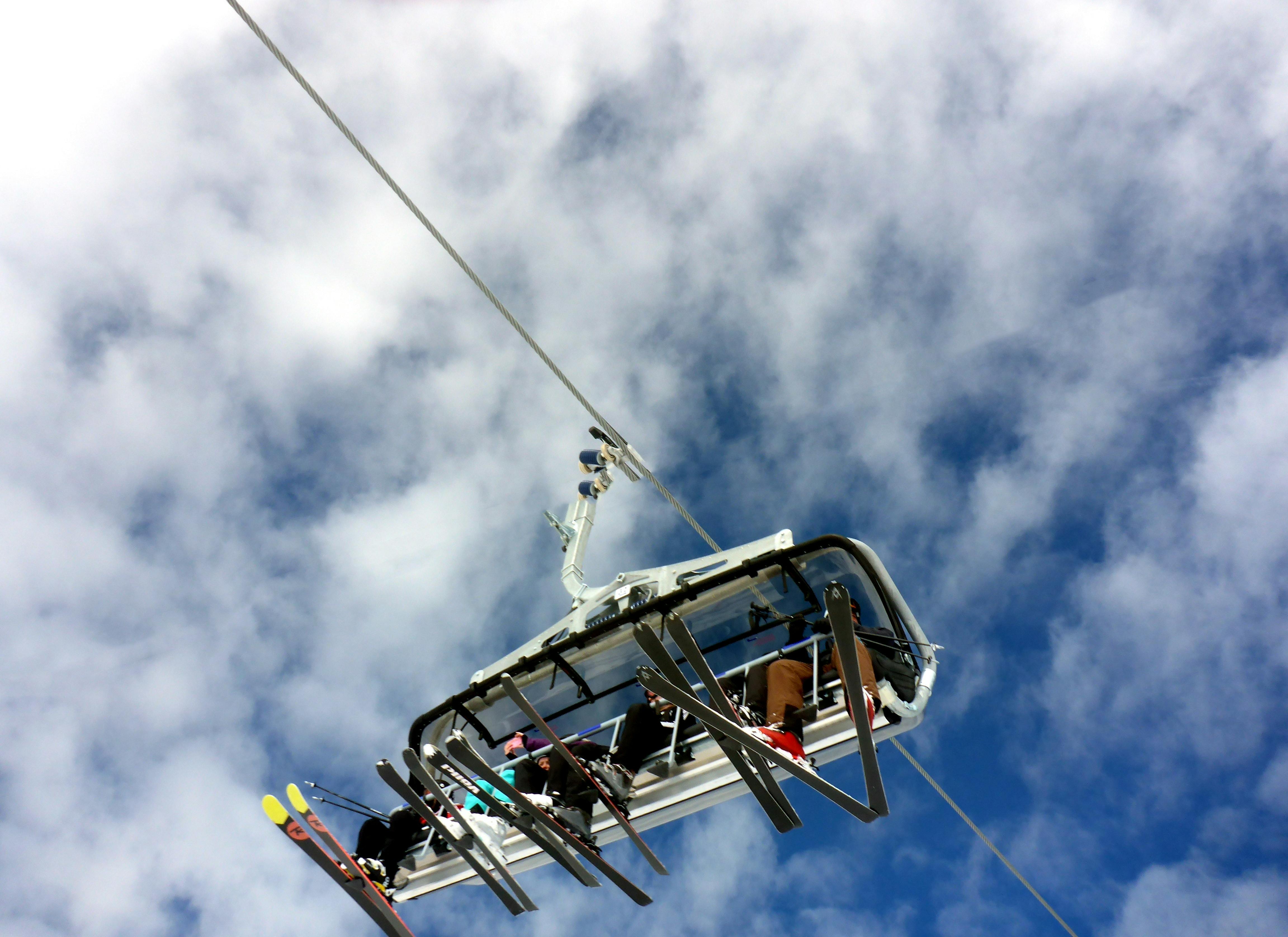 A view of a chairlift with four skiers on it from below.