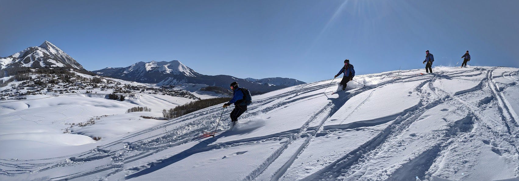 Three skiers turning down a snowy ski slope. 