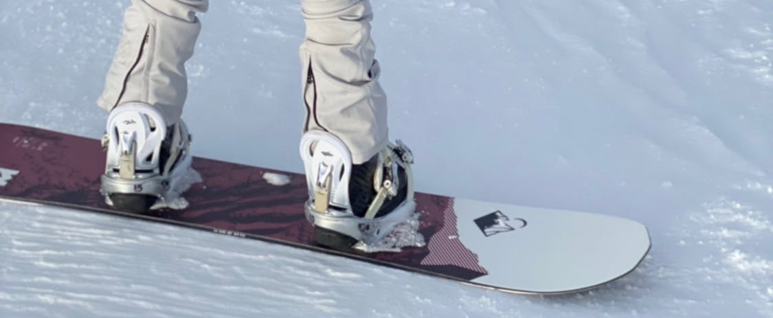 Close up of the Weston Snowboards Riva Women's Snowboard as someone snowboards on it. 